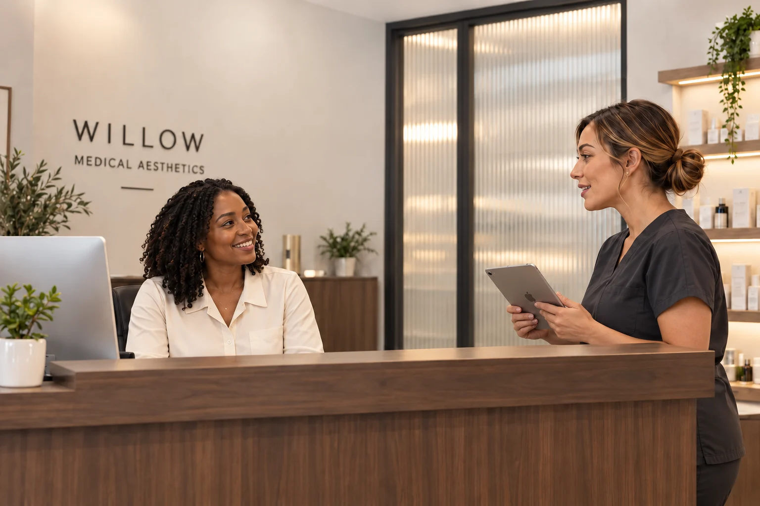 A receptionist smiling at a clinician holding an iPad at the front desk of a small aesthetic clinic.