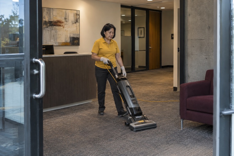 Cleaner vacuuming an office lobby
